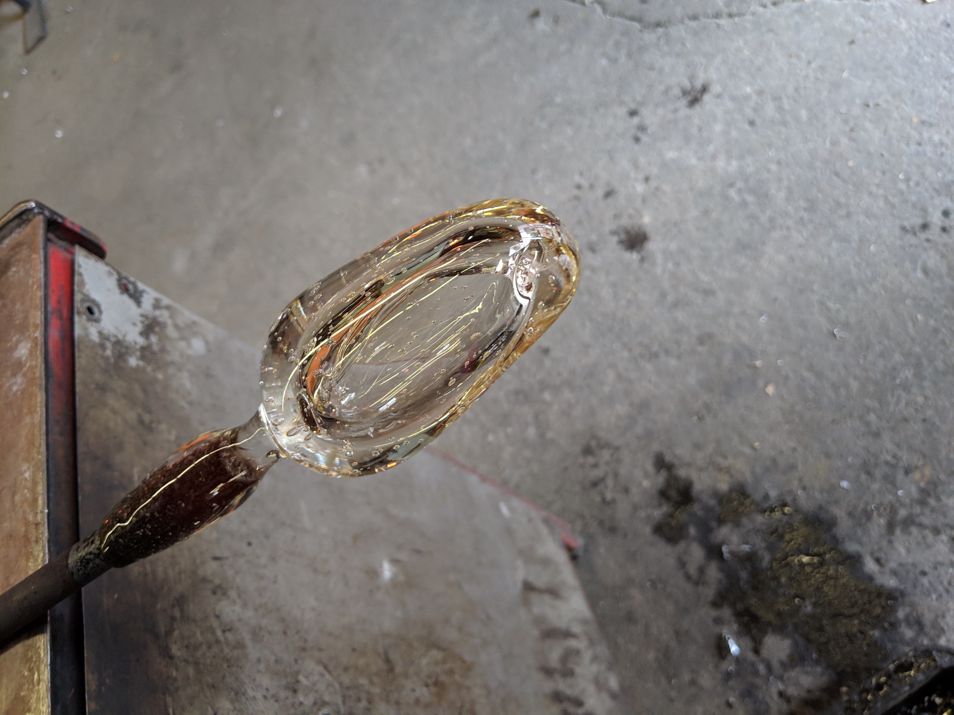 A chunk of glass on a punty with a filament running along the side