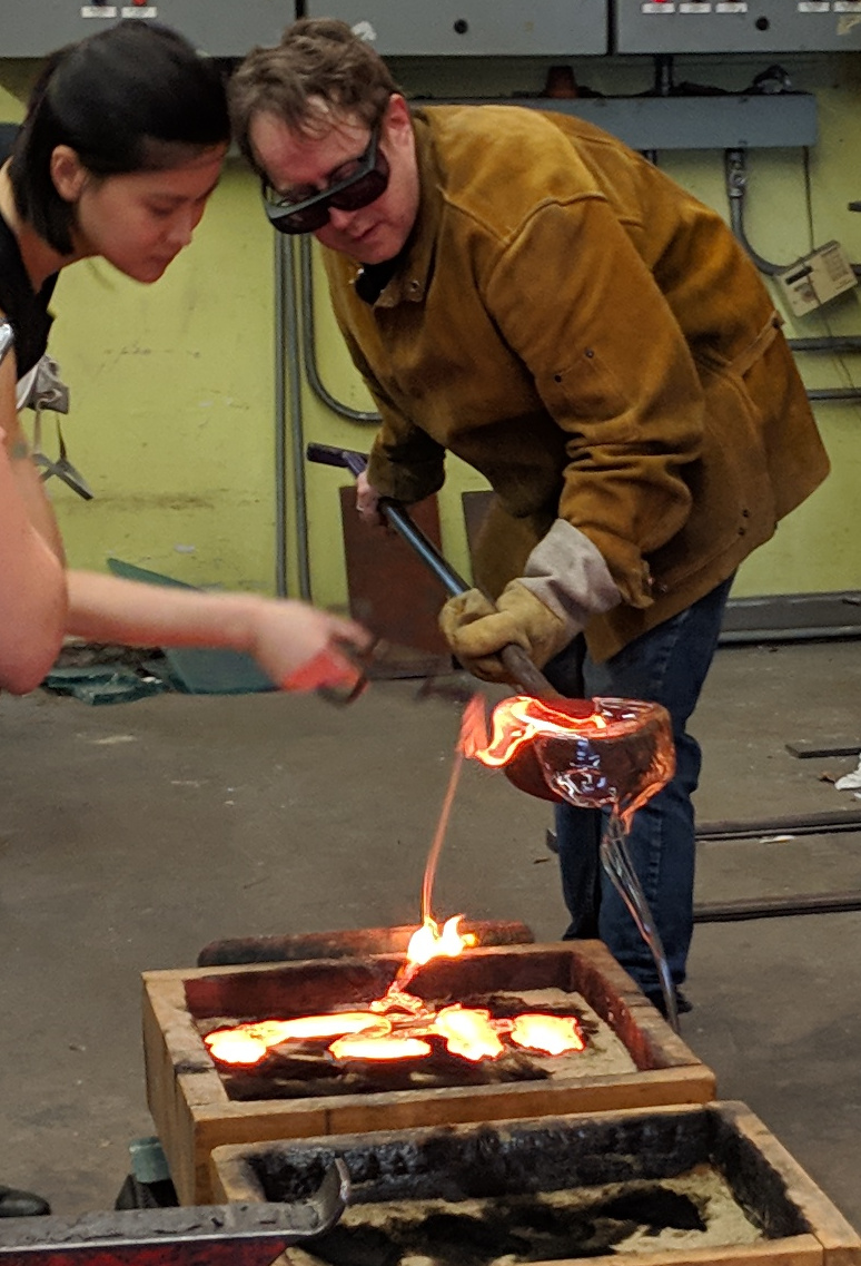 Chris pouring molten glass into a sand mold